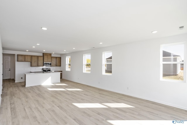 unfurnished living room featuring sink and light wood-type flooring