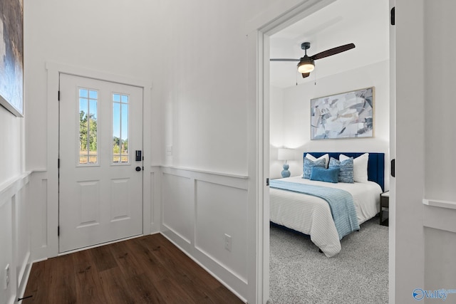 interior space featuring a wainscoted wall, ceiling fan, a decorative wall, and dark wood-style flooring