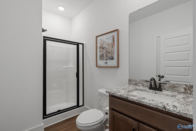 full bathroom featuring toilet, a shower stall, wood finished floors, and vanity