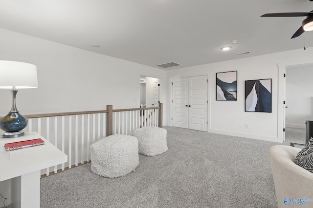 living area with ceiling fan, carpet floors, visible vents, and baseboards