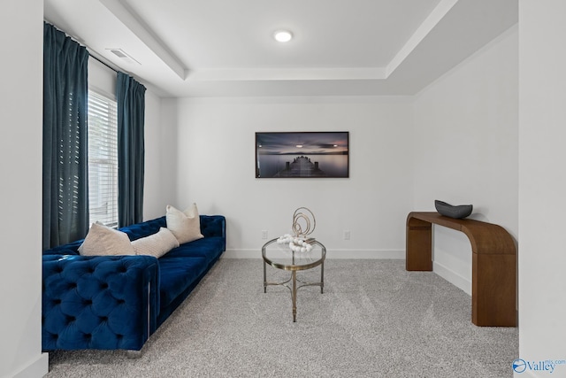 living room with a tray ceiling, carpet flooring, visible vents, and baseboards