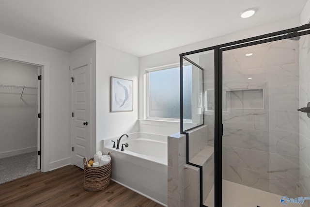 full bath featuring baseboards, wood finished floors, a garden tub, a spacious closet, and a shower stall