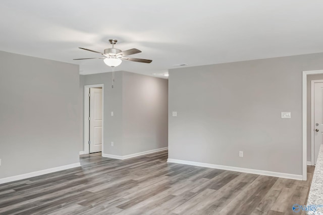 unfurnished room featuring visible vents, baseboards, wood finished floors, and a ceiling fan