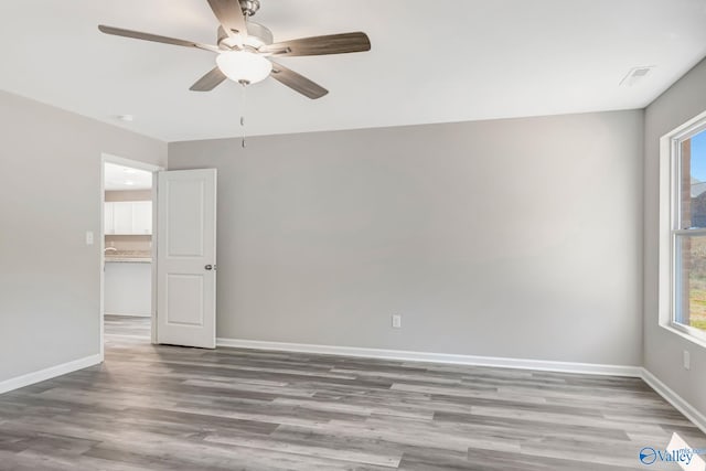 spare room with visible vents, wood finished floors, baseboards, and ceiling fan