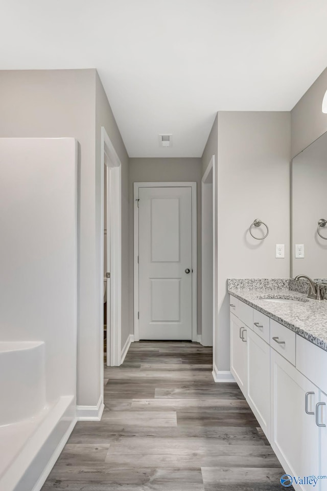 full bath featuring vanity, visible vents, wood finished floors, and baseboards