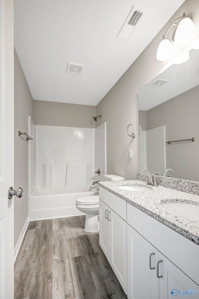 bathroom with shower / tub combination, wood finished floors, visible vents, and a sink