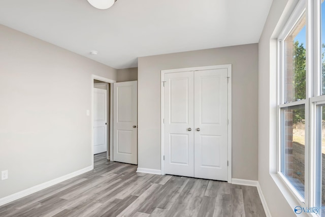 unfurnished bedroom with baseboards, a closet, and light wood-type flooring