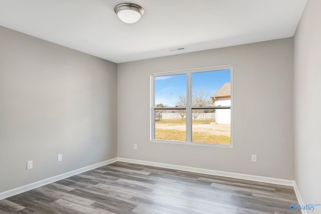 spare room with visible vents, baseboards, and wood finished floors