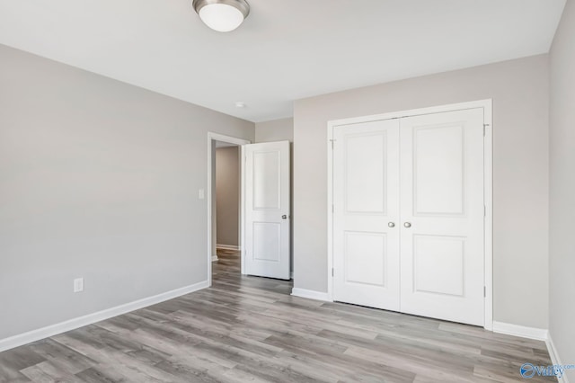 unfurnished bedroom with a closet, baseboards, and light wood finished floors