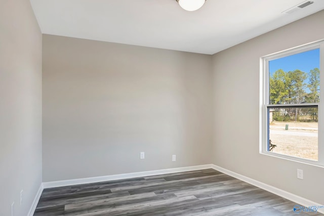 empty room featuring visible vents, baseboards, and dark wood-style flooring