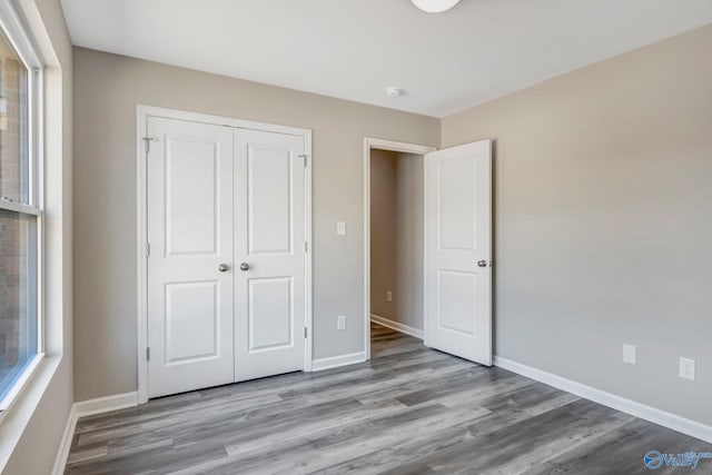 unfurnished bedroom with a closet, baseboards, and wood finished floors