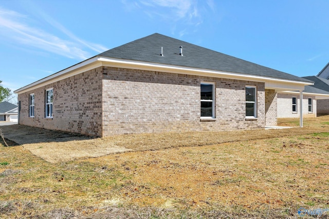 back of property with a yard and brick siding