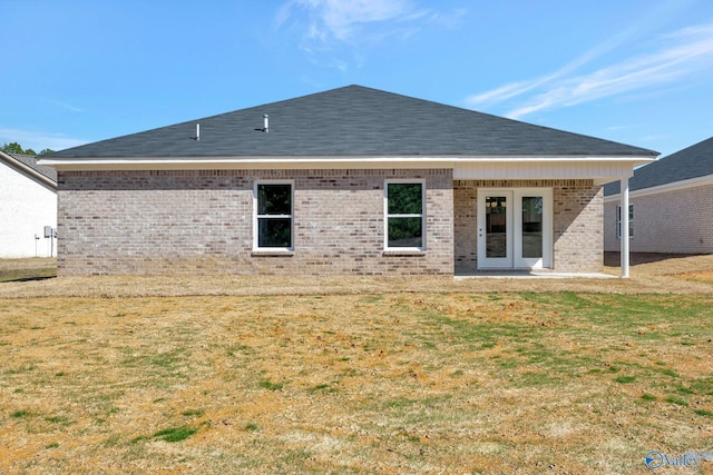 back of property featuring a yard, brick siding, roof with shingles, and french doors