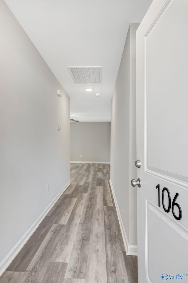 corridor with visible vents, baseboards, and wood finished floors