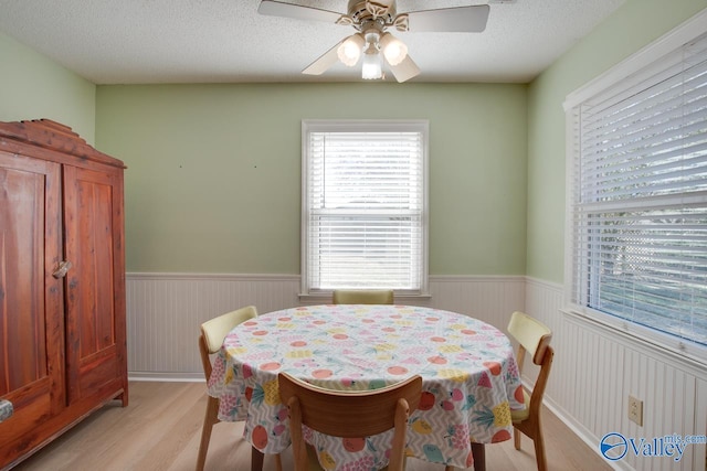 dining room featuring a textured ceiling, light hardwood / wood-style flooring, and ceiling fan