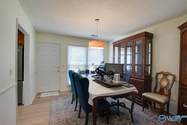 dining space with a textured ceiling and light wood-type flooring