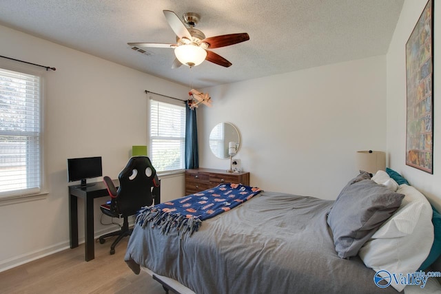 bedroom featuring light wood-type flooring, a textured ceiling, and ceiling fan