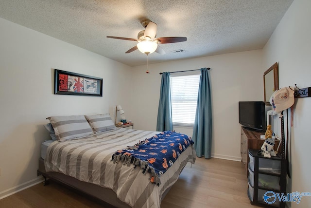 bedroom featuring ceiling fan, wood-type flooring, and a textured ceiling