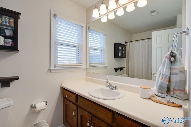 bathroom featuring vanity, walk in shower, and toilet