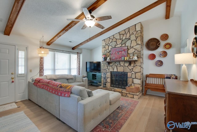 living room with a fireplace, lofted ceiling with beams, a textured ceiling, and light wood-type flooring