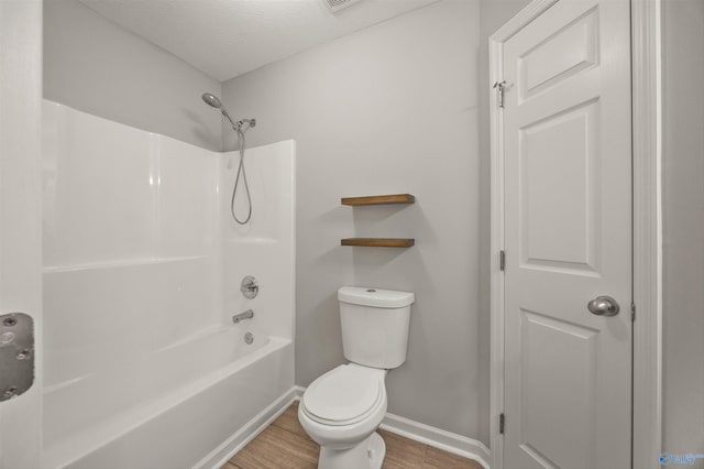 bathroom featuring wood-type flooring,  shower combination, a textured ceiling, and toilet