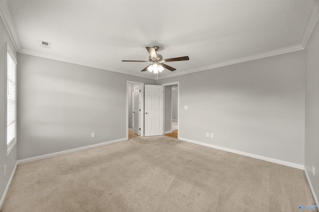 carpeted spare room featuring ornamental molding, ceiling fan, and plenty of natural light