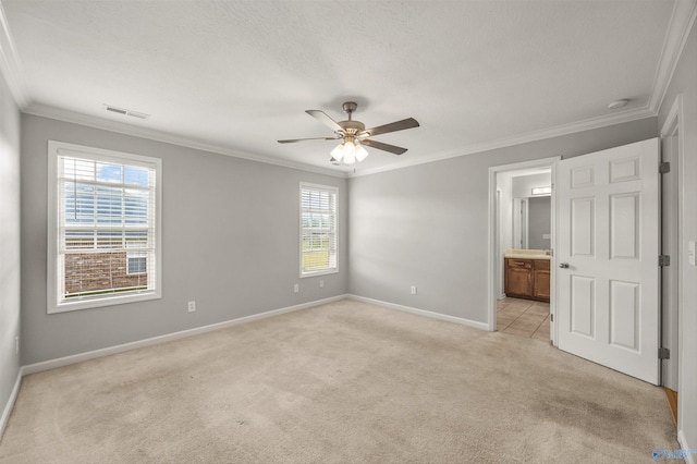 unfurnished bedroom featuring multiple windows, connected bathroom, light carpet, and ceiling fan