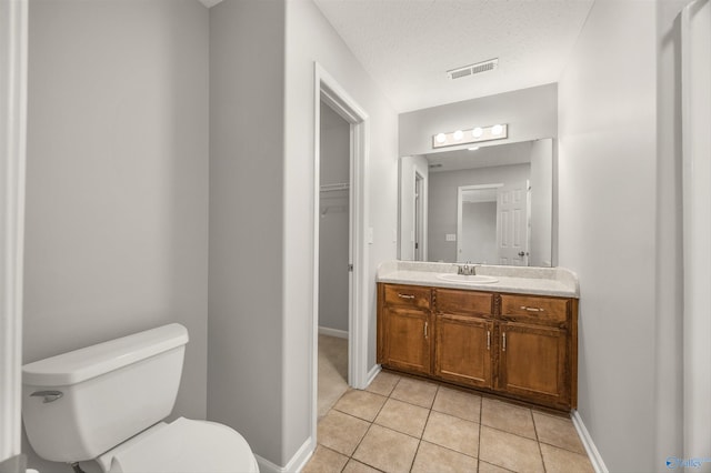 bathroom featuring a textured ceiling, tile patterned flooring, vanity, and toilet