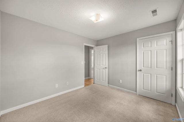 unfurnished bedroom featuring light carpet and a textured ceiling