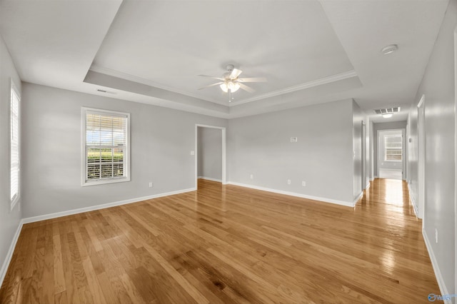 unfurnished room featuring light wood-type flooring, a tray ceiling, and ceiling fan