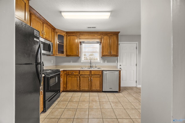 kitchen with black appliances, a textured ceiling, light tile patterned floors, and sink