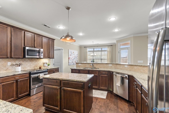 kitchen featuring sink, appliances with stainless steel finishes, hanging light fixtures, light stone counters, and kitchen peninsula