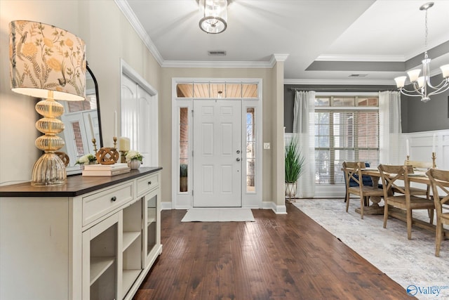 foyer with ornamental molding, dark hardwood / wood-style flooring, and a chandelier