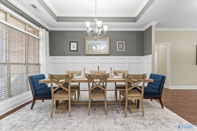 dining area featuring crown molding, a tray ceiling, a chandelier, and hardwood / wood-style floors