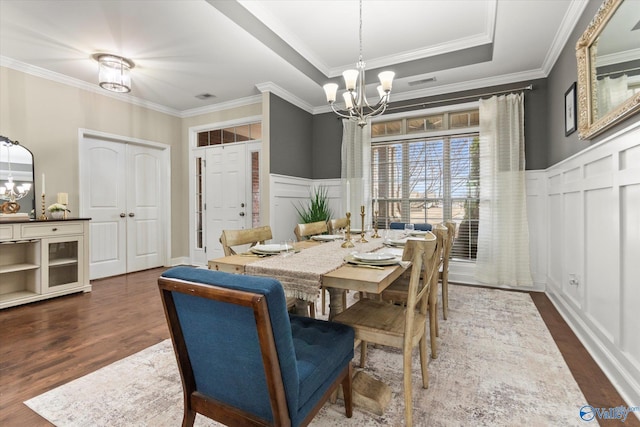 dining room with crown molding, dark wood-type flooring, an inviting chandelier, and a tray ceiling