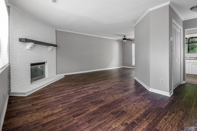 unfurnished living room with crown molding, ceiling fan, dark hardwood / wood-style floors, and a brick fireplace