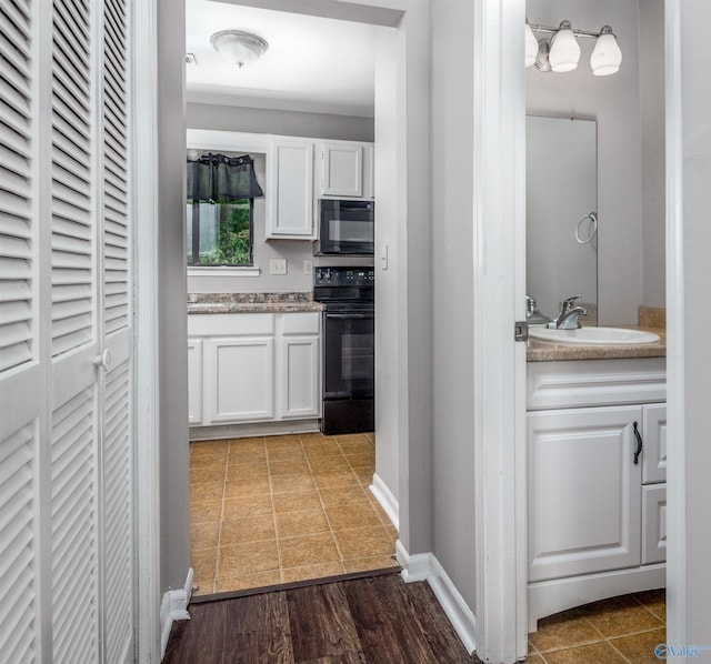 kitchen featuring white cabinetry, tile patterned floors, sink, and black appliances