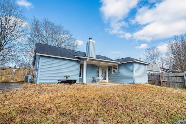 back of house with central AC, a patio area, and a lawn