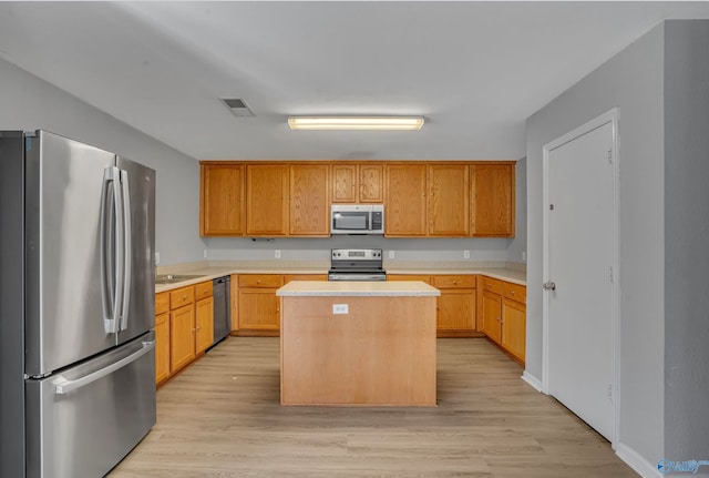 kitchen with sink, appliances with stainless steel finishes, light hardwood / wood-style flooring, and a kitchen island