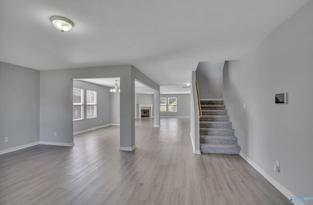 unfurnished living room featuring an inviting chandelier, light hardwood / wood-style flooring, and a healthy amount of sunlight