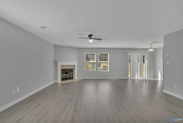 unfurnished living room with a tiled fireplace, ceiling fan, and light hardwood / wood-style flooring