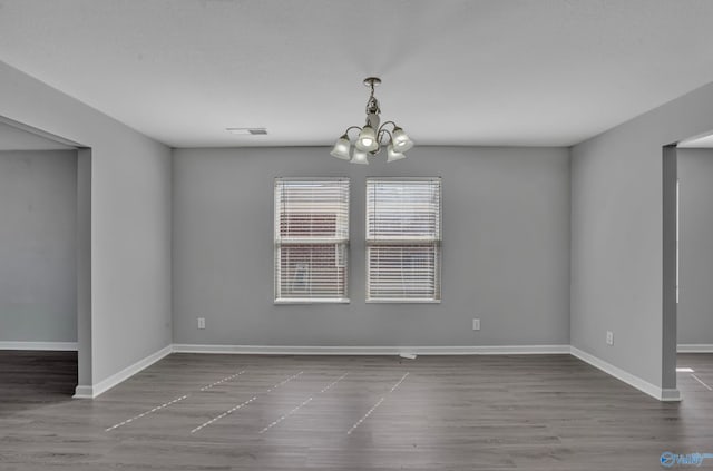 empty room with a chandelier and wood-type flooring