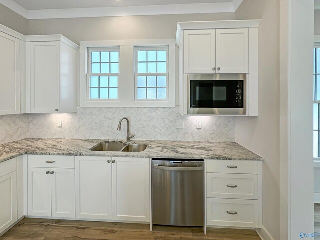 kitchen with built in microwave, stainless steel dishwasher, white cabinetry, and sink