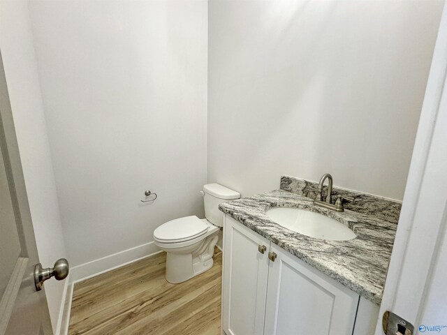 bathroom with vanity, toilet, and hardwood / wood-style flooring