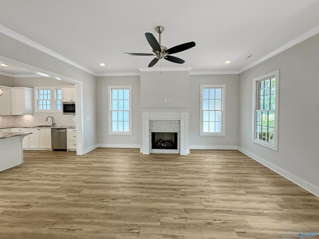 unfurnished living room featuring light hardwood / wood-style flooring, ceiling fan, crown molding, and a high end fireplace