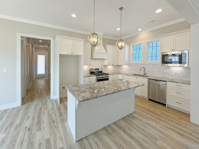 kitchen with appliances with stainless steel finishes, a center island, white cabinets, and light stone counters