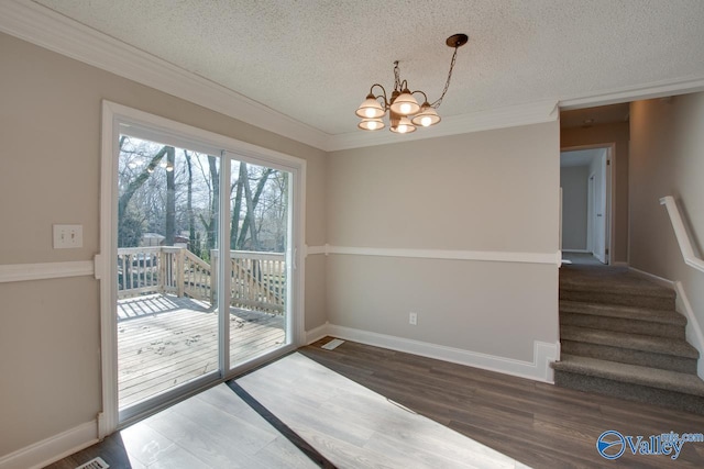 doorway featuring a notable chandelier, ornamental molding, dark wood-type flooring, and a textured ceiling