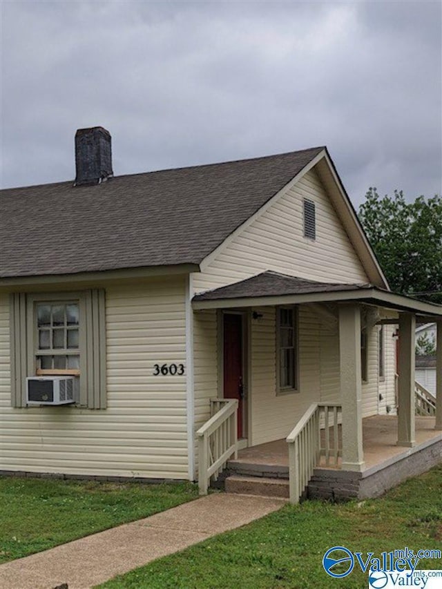 view of front of property featuring a porch, cooling unit, and a front yard