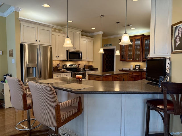 kitchen with a center island, glass insert cabinets, backsplash, dark countertops, and appliances with stainless steel finishes