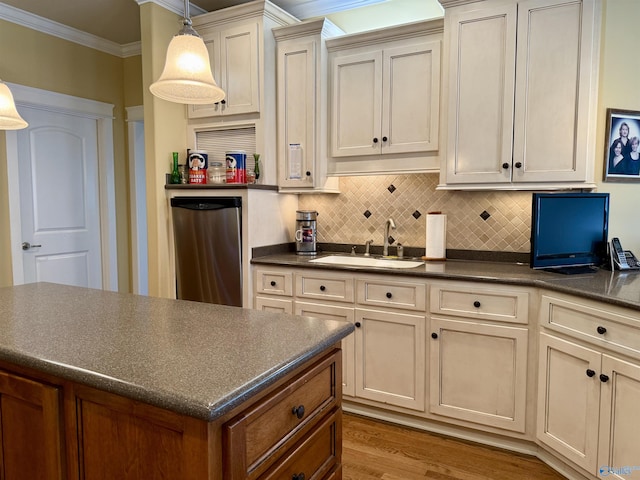 kitchen with a sink, cream cabinets, crown molding, decorative backsplash, and dark countertops